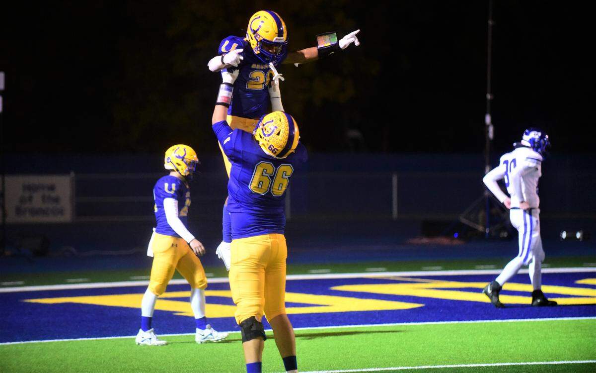 Dos Palos freshman running back Andre Flores (26) is lifted up by a teammate after he scored his second touchdown in a 28-27 playoff win over Morro Bay on Thursday, Nov. 10, 2022.