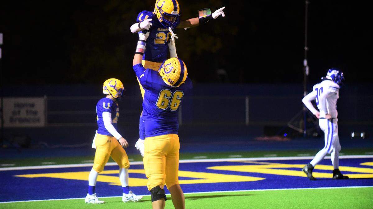 Dos Palos freshman running back Andre Flores (26) is lifted up by a teammate after he scored his second touchdown in a 28-27 playoff win over Morro Bay on Thursday, Nov. 10, 2022.