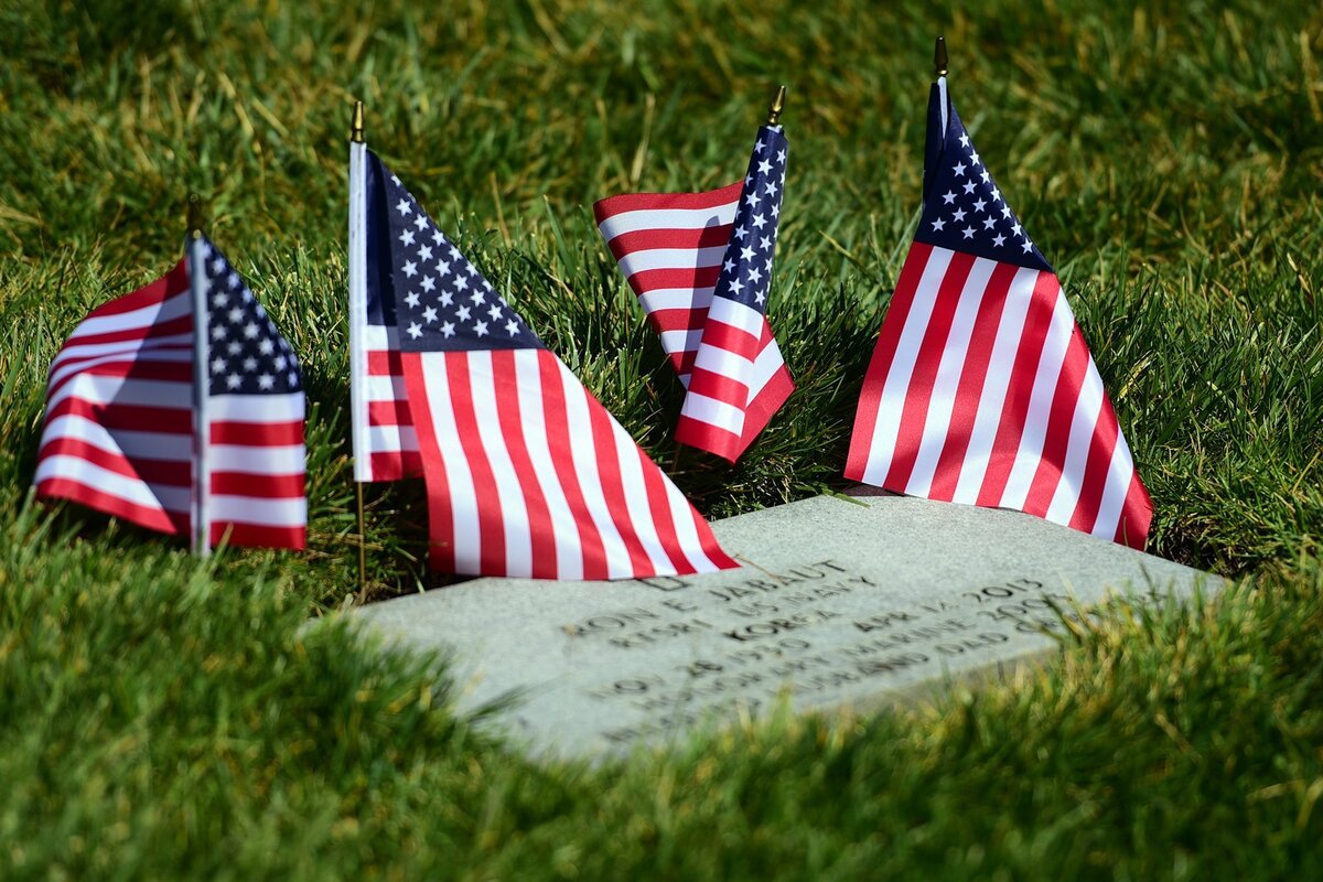 A headstone is decorated with flags on Sunday, May 27, 2018, at San Joaquin Valley National Cemetery in Santa Nella following a ceremony for Memorial Day.