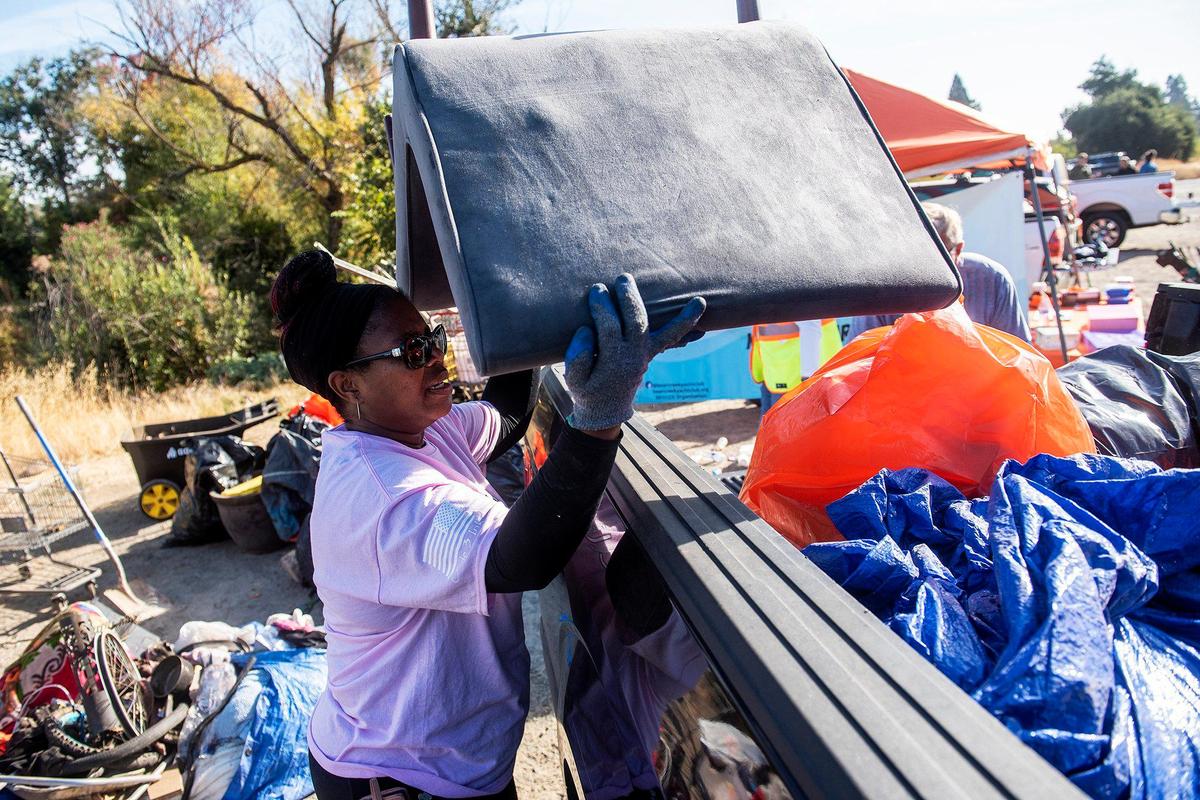 Rhonda Batson, 52, of Merced, places items collected from along the banks of Bear Creek near McKee Road, into the bed of a pickup tuck during a cleanup event presented by the Merced non-profit Bear Creek Yacht Club in Merced, Calif., on Saturday, Oct. 14, 2023. Batson, serves as the non-profit’s secretary and volunteers with several other community groups.