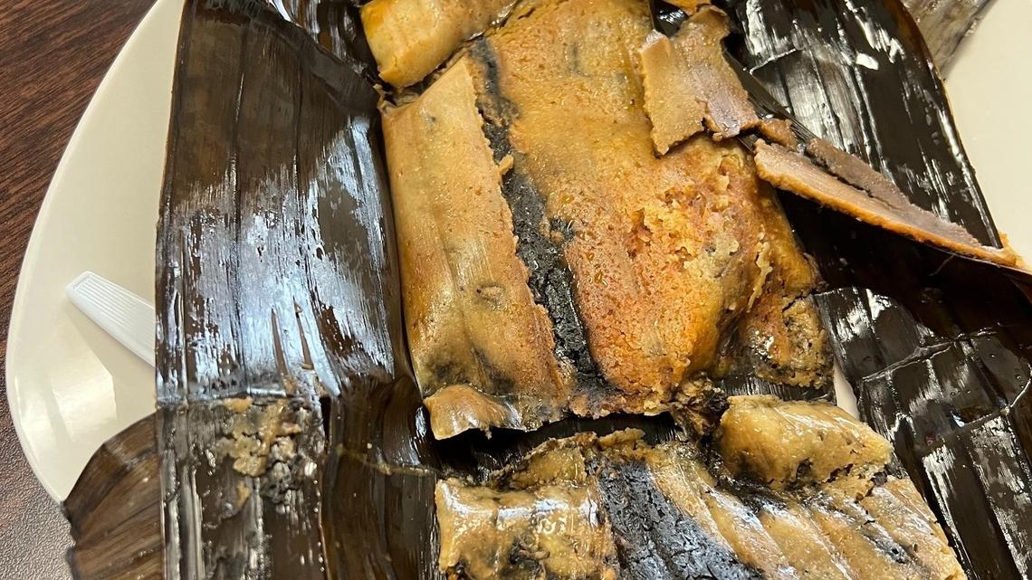 A black mole sauce tamale sits on top of a glossy banana leaf at El Sabor de Oaxaca on Wednesday Dec. 18. This tamale is $3.78 and is filled with a thick sauce containing walnuts, plantains, chocolate, cinnammon, pasilla chile, raisins and more. A spicy and non-spicy option is available for purchase.