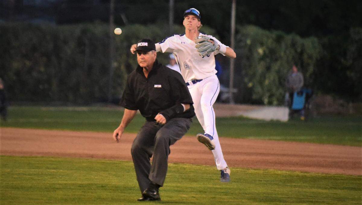 Atwater High senior shortstop Cole Hazel throws to first base as umpire Tim Arnsberg looks on during a game against Merced on Friday, April 30, 2022 at Memorial Ballpark in Atwater, Calif.