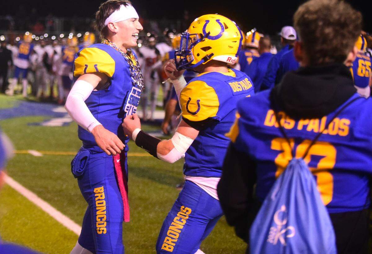 Dos Palos High School senior quarterback Peyton Van Worth (5) celebrates with fellow senior Drake Hennagan (3) after the Broncos defeated Coalinga 21-20 to win the West Sierra League championship on Friday, Oct, 28, 2023 at Bill Hume Stadium in Dos Palos, Calif.