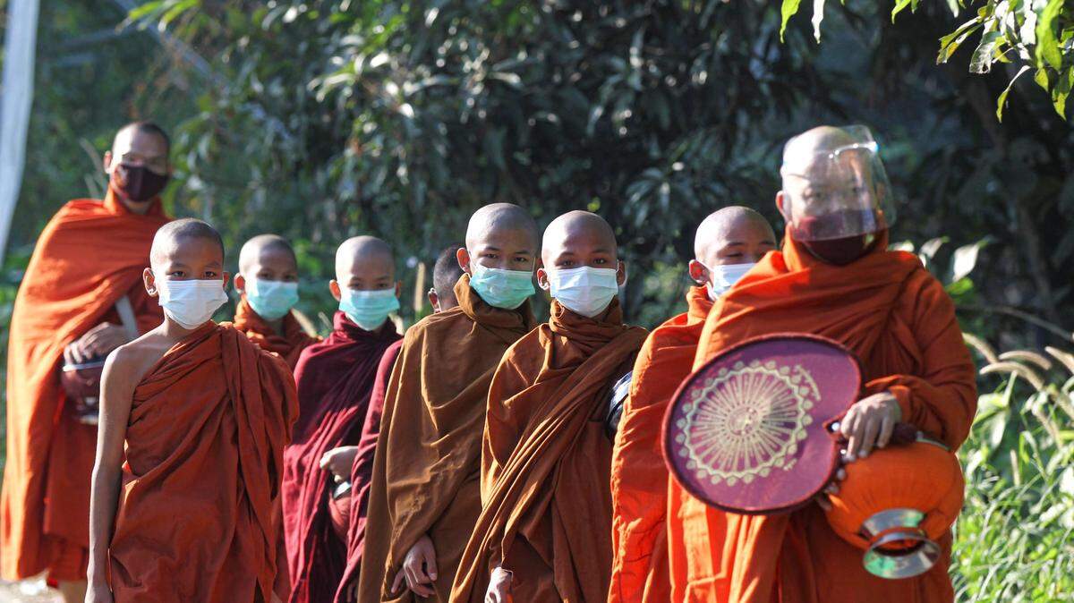Buddhist monks wearing a face shield and masks to help curb the spread of the coronavirus walk to collect their morning alms from Buddhist devotees Thursday, Dec. 10, 2020, on the outskirts of Yangon, Myanmar. (AP Photo/Thein Zaw)