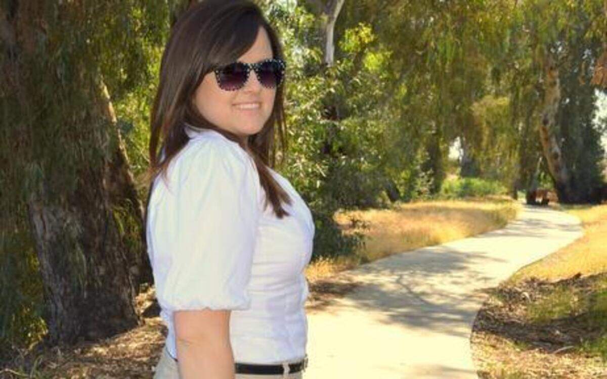 Fashion blogger Michelle Oliver pairs linen pants with a white shirt and a black belt for a professional look that is comfortable in the summer heat. A mint-green clutch adds a little zip.
