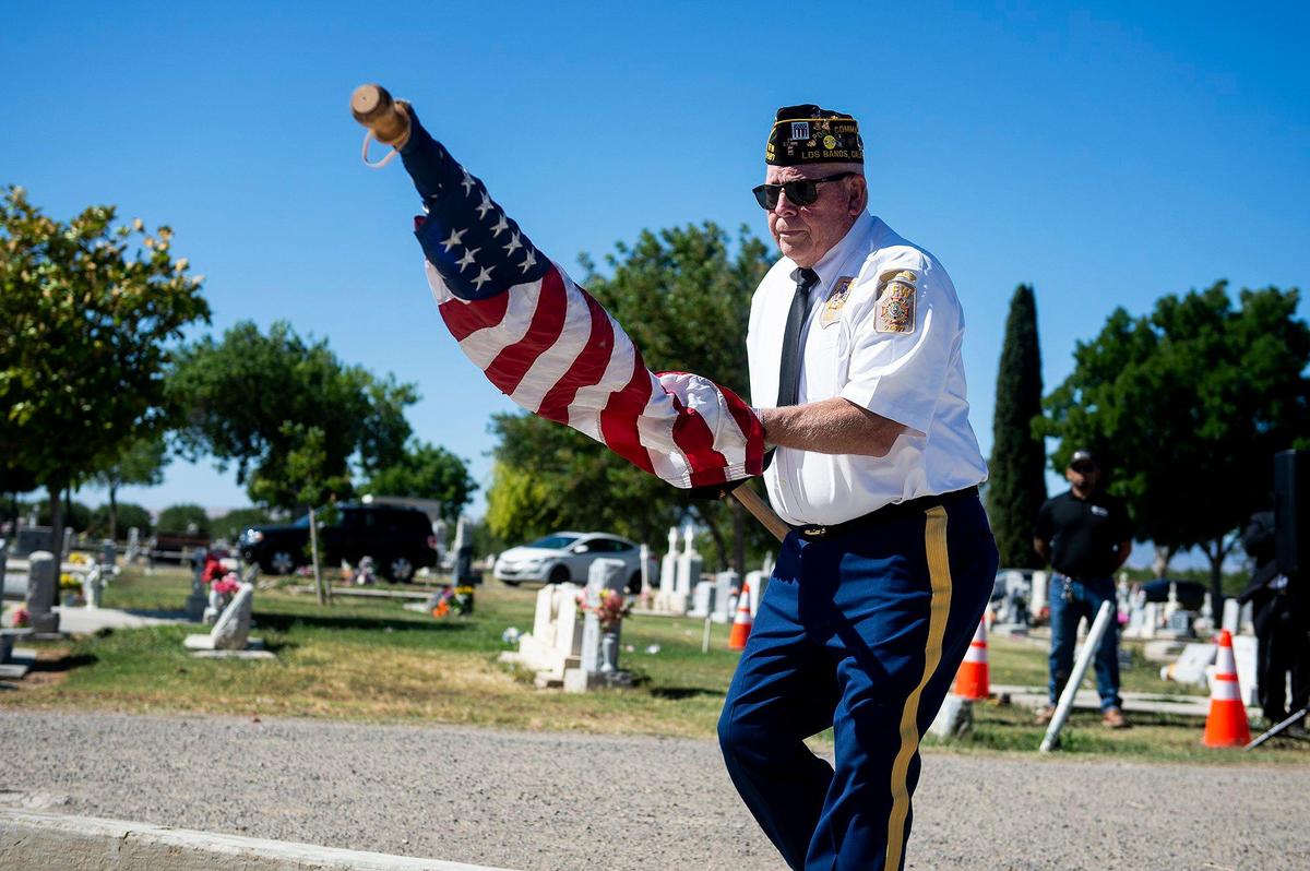 Michael Hughes, commander of V.F.W. Post 2487 places the American flag at a memorial, during a Memorial Day ceremony at the Los Banos Cemetery, located at 16575 Center Avenue in Los Banos, Calif., on Monday, May 30, 2022.