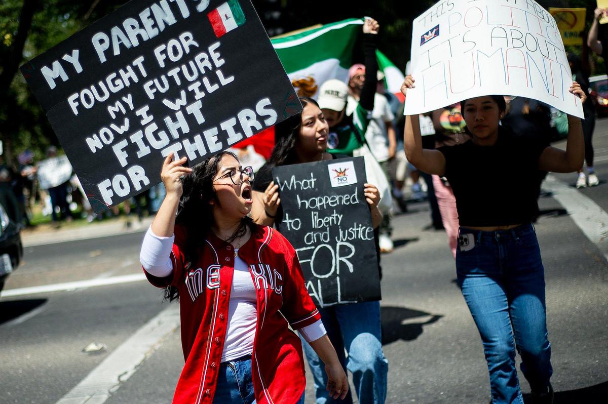 A woman who identified herself as Camila, holds a sign as she and other protesters take part in a “No Kings” protest in Merced, Calif., on Saturday, June 14, 2025.