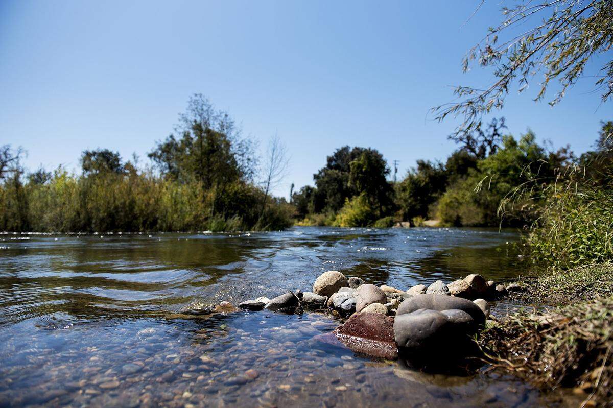 The Merced River flows over a group of rocks on the riverbank near the historic Shaffer Bridge in Winton, Calif., on Monday, Sept. 17, 2018. 