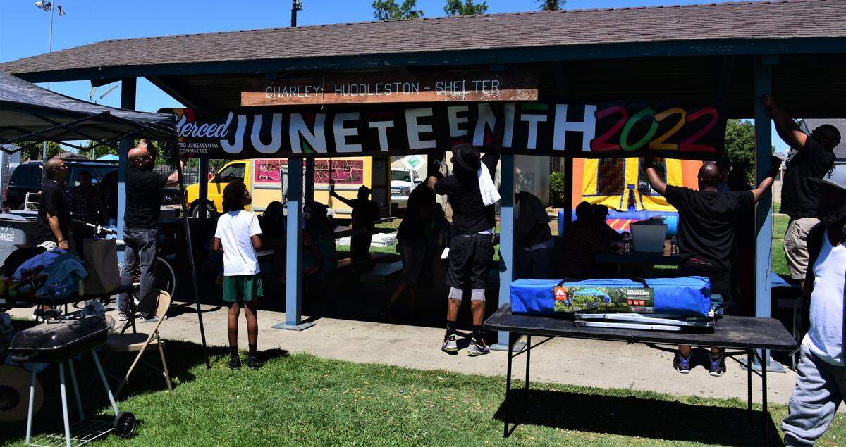 Members of the Positive Brothers United group help put up a Merced Juneteenth 2022 banner during a Juneteenth celebration in McNamara Park in Merced, Calif. on Saturday, June 18, 2022.