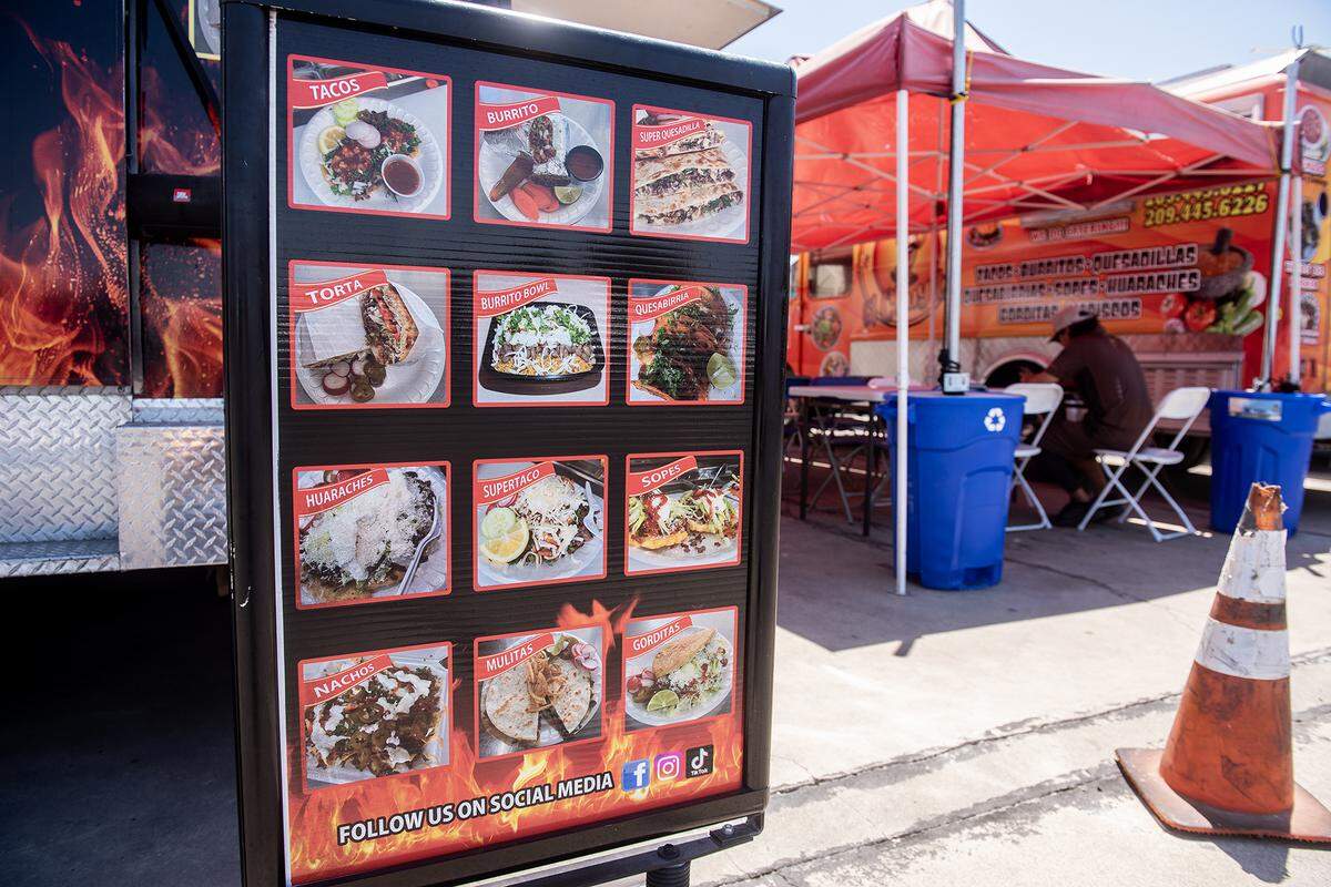 A sign features menu offerings from the El Tacoloco Taqueria food truck at a food truck parking area in the lot of Courtesy Rent a Car, 1055 W. 15th Street in Merced, Calif., on Tuesday, Aug. 12, 2025. The location currently hosts up to nine food trucks offering various cuisine options. 