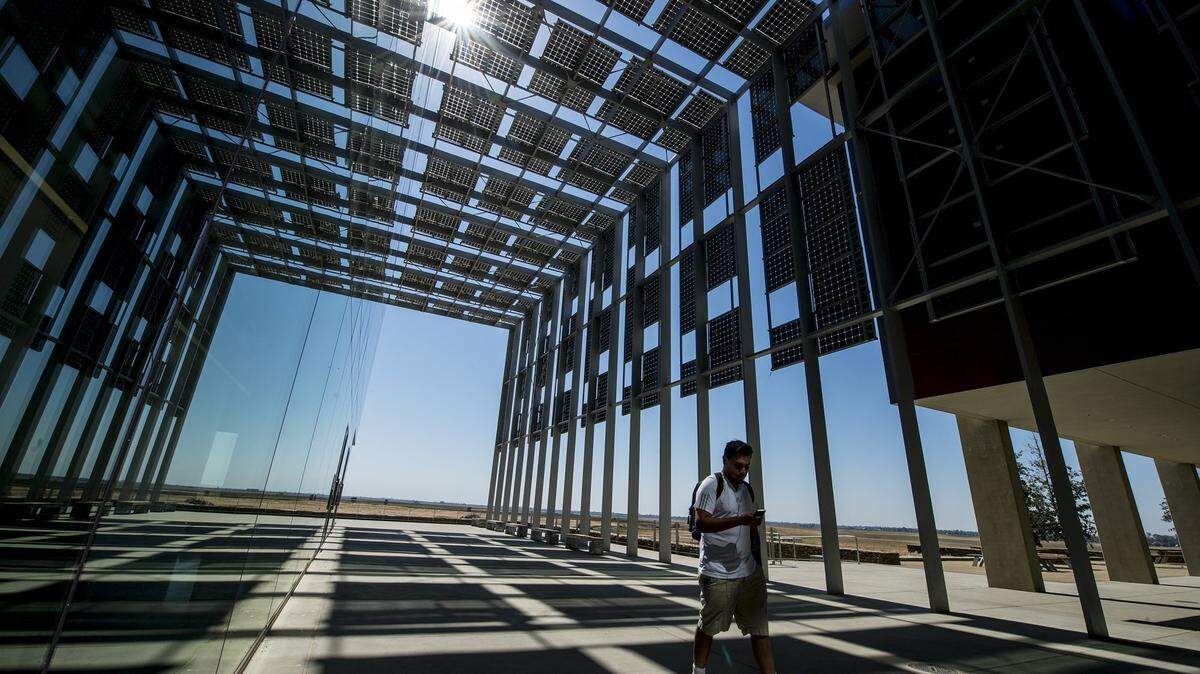 A student walks beneath solar panels on the Science and Engineering Building 2 on the University of California, Merced campus Tuesday, Sept. 6, 2016. The university was named as one of the Sierra Club’s “Cool Schools” for its sustainability efforts throughout the campus. According to director of news and social media, James Leonard, Director of News and Social Media, UC Merced is the only school in the nation to have all of its buildings certified by U.S. Green Building Council’s Leadership in Energy and Environmental Design of (LEED).