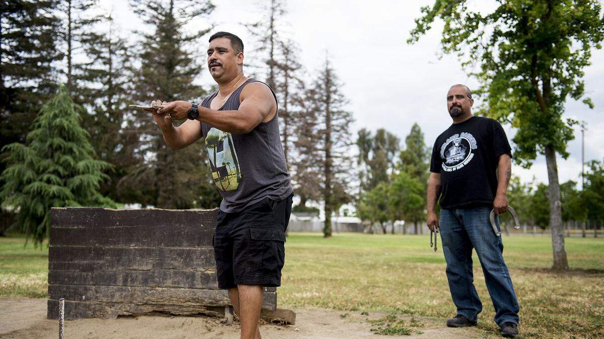 Ray Cervantes, 42, of Merced, left, prepares to throw during a game of horseshoes against friend David Perez, 42, of Merced, right, at Joe Herb Park in Merced, Calif., on Friday afternoon, May 25, 2018.