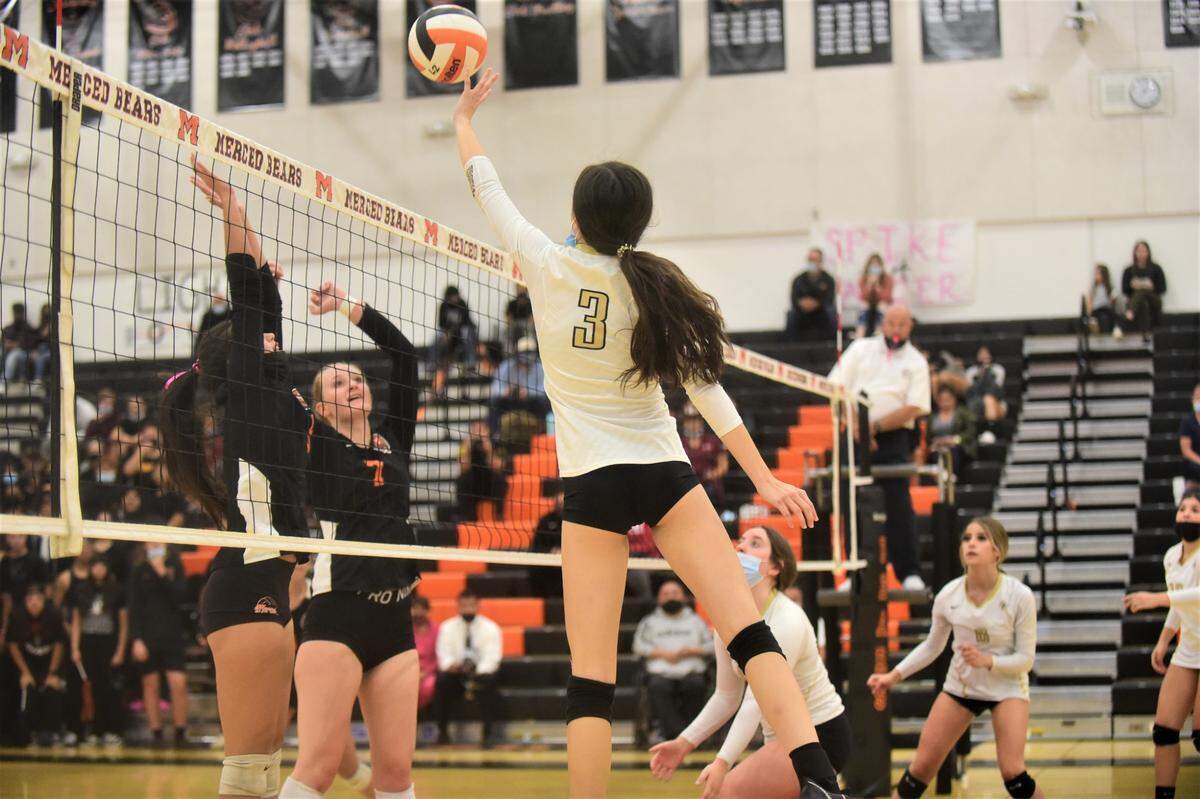 Buhach Colony’s Celina Henn hits the ball over the Merced block during a match at Merced High School on Tuesday, Oct. 19, 2021.