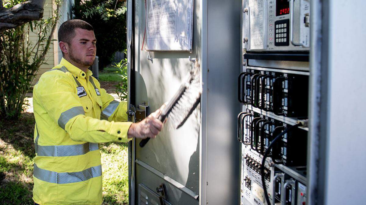 Tanner Harkreader, 28, a lead lighting technician with the City of Merced, performs routine maintenance on a traffic signal cabinet at the intersection of Olive Avenue and Parsons Avenue in Merced, Calif., on Thursday, July 31, 2025. 