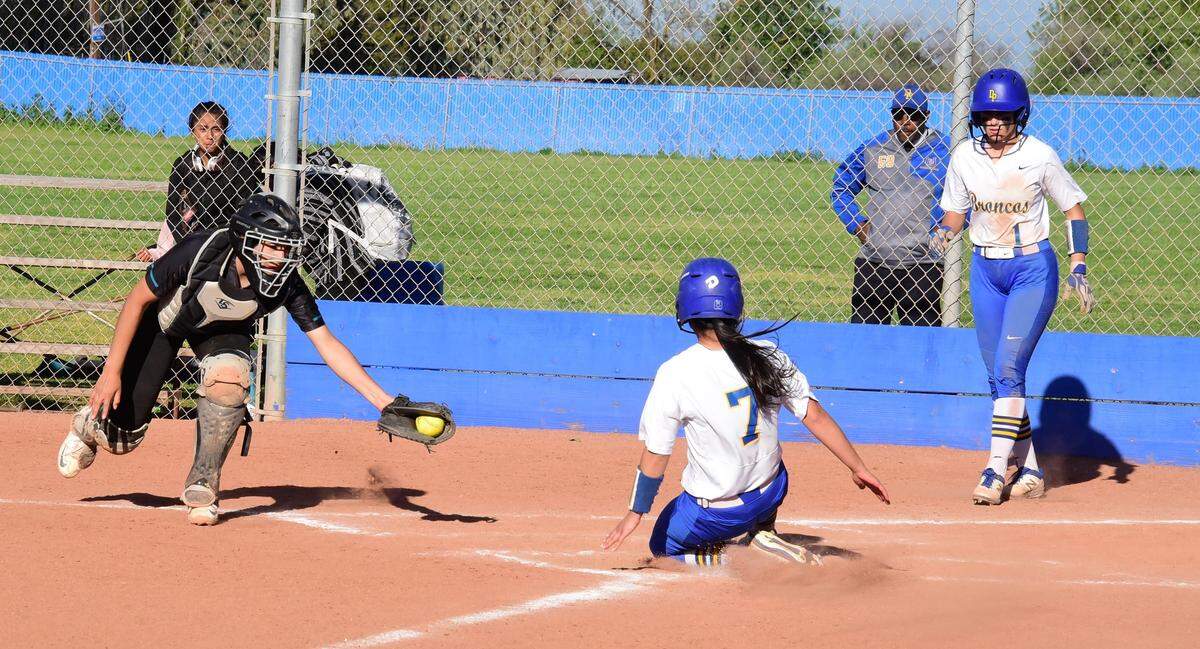 Dos Palos High senior Lizzete Rodriguez slides home safely as teammate Priscilla Glase looks on during the Broncos’ 11-0 win over Mendota on Tuesday, April 9, 2019 at Dos Palos High in Dos Palos, Calif.