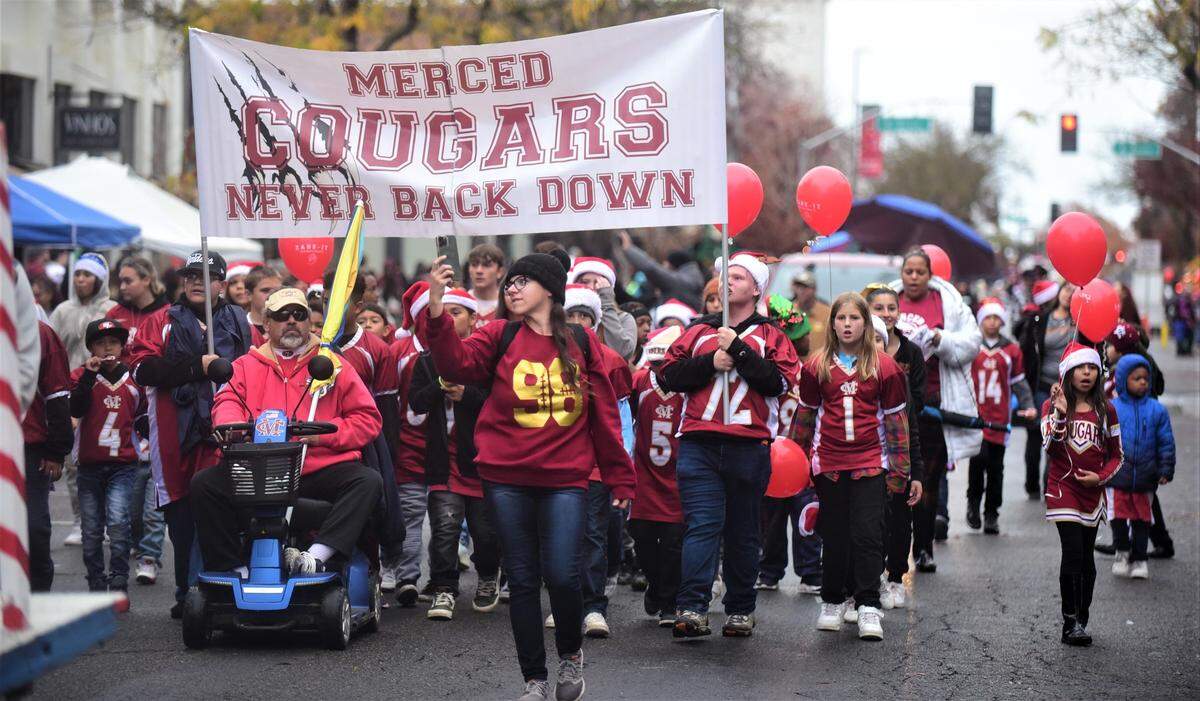 The Merced Cougars youth football players and cheerleaders make their way down Main Street during the Merced Christmas Parade on Saturday, Dec. 3, 2022.