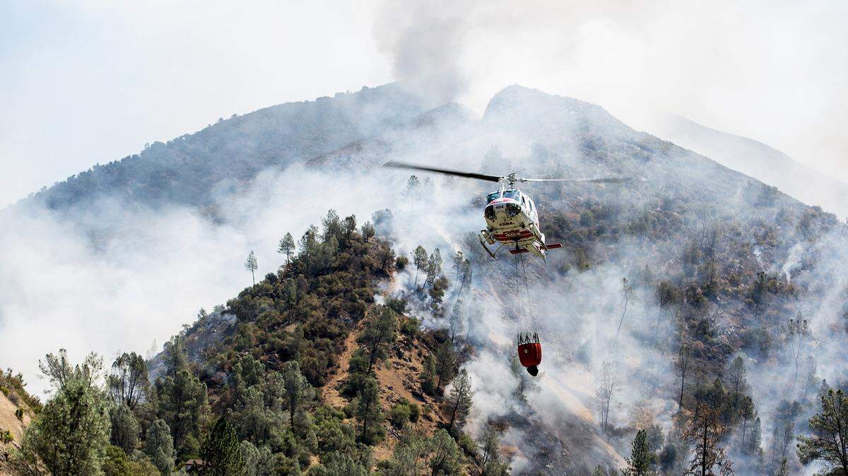 A helicopter gathers water from the Merced River to fight the Ferguson fire along steep terrain behind the Redbud Lodge near El Portal along Highway 140 in Mariposa County, Calif., on Saturday, July 14, 2018.