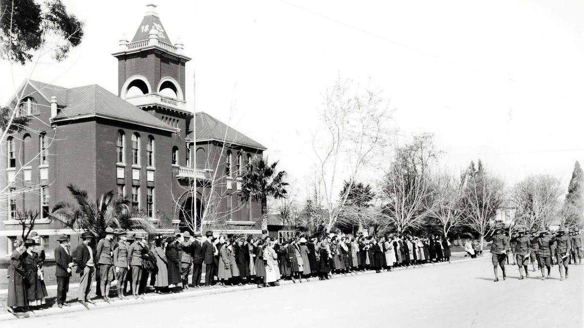 The members of the Merced Union High School Cadet Corps received their commissions and appointments after passing in review before the faculty, student body, family members, and fellow cadets from Le Grand High School on February 21, 1919. Seen in the back is the Merced Union High School on M Street built in 1897.