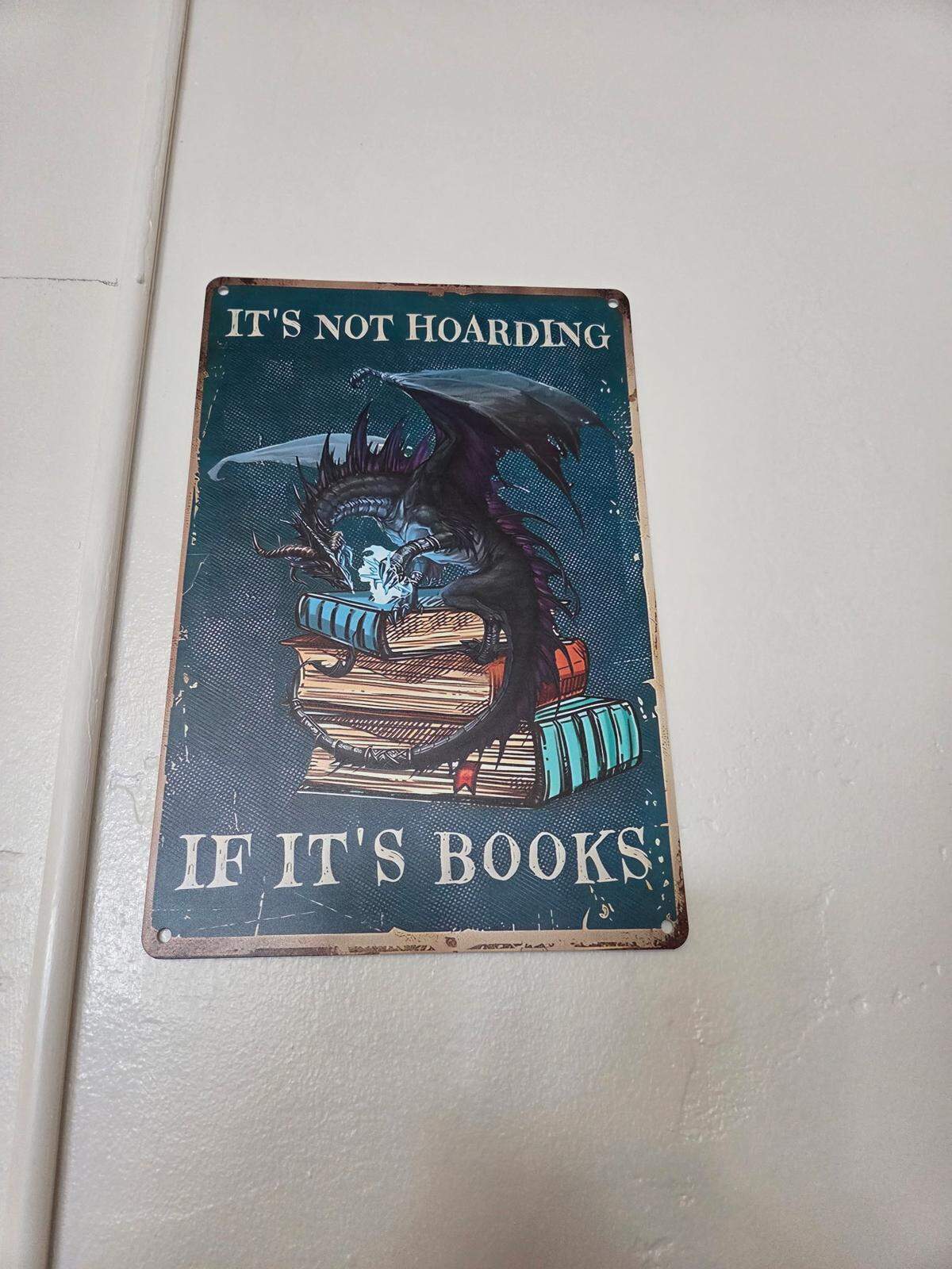 A sign with a picture of books and the words “It’s not hoarding if it’s books”