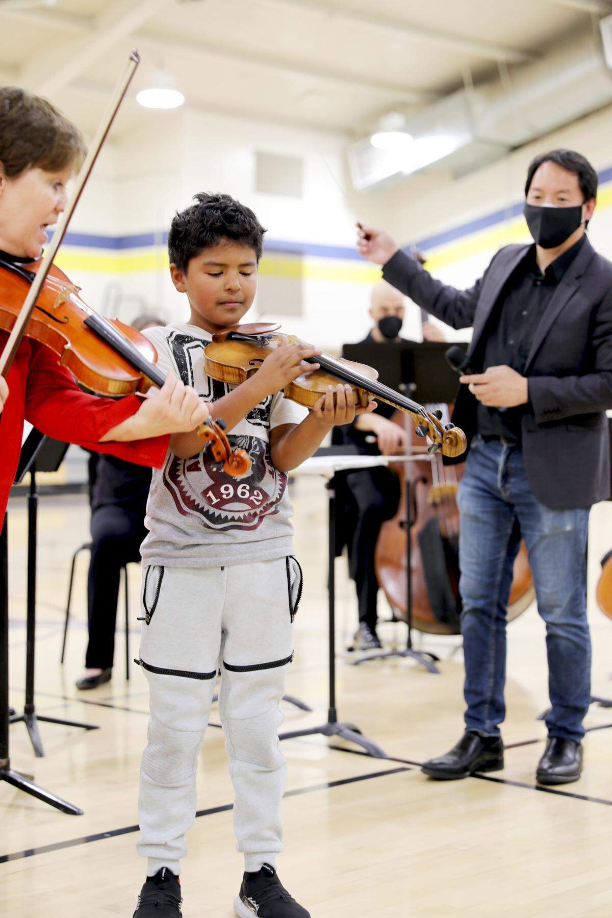 A student from Marks Elementary School joins Dawn Harms and Merced Symphony Orchestra Conductor Ming Luke in a bit for a performance at Dos Palos High School.