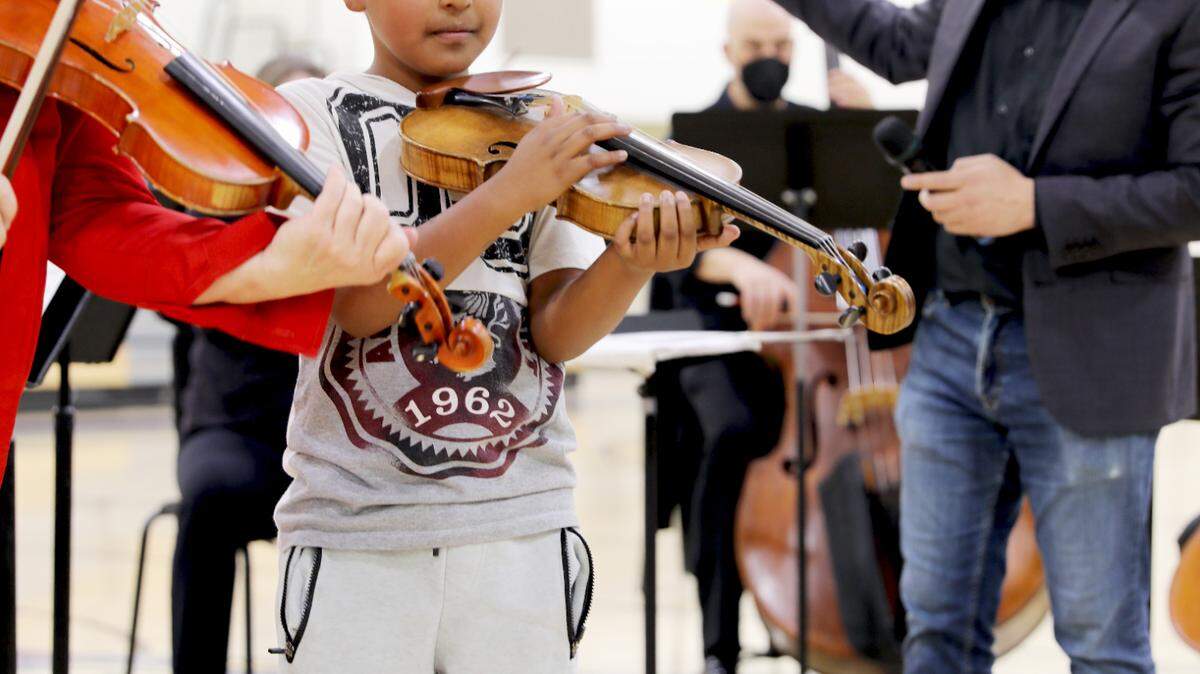 A student from Marks Elementary School joins Dawn Harms and Merced Symphony Orchestra Conductor Ming Luke in a bit for a performance at Dos Palos High School.