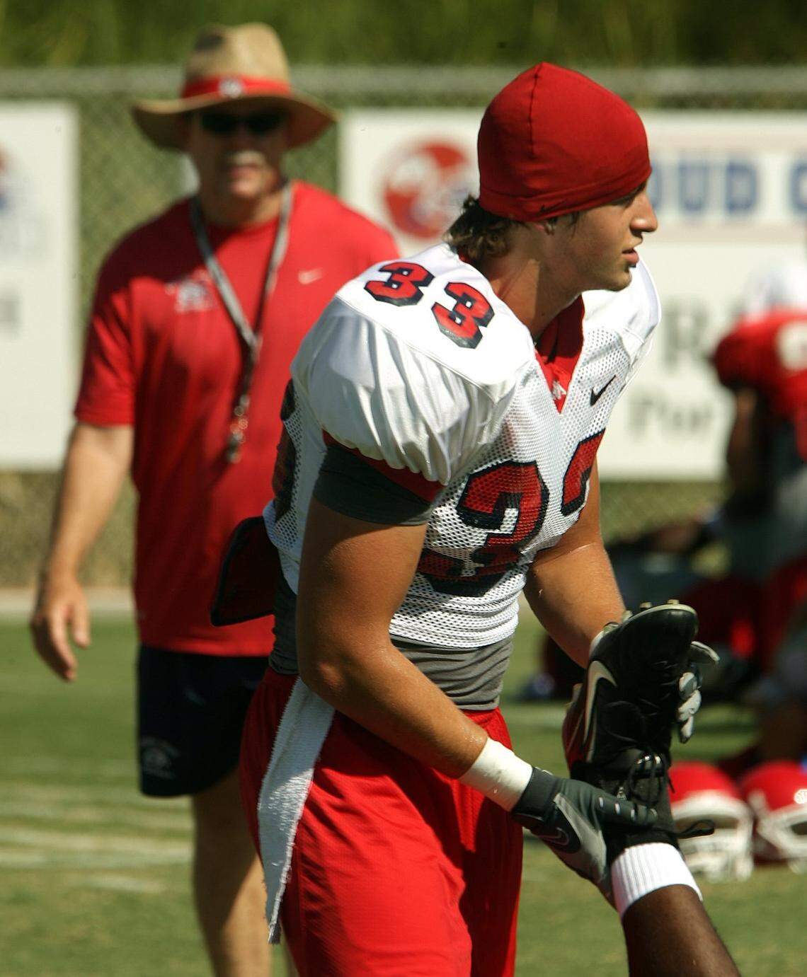 Fresno State football player Zak Hill stretches out a teammate while his father, head coach Pat Hill, walks nearby during practice in this 2007 file photo.