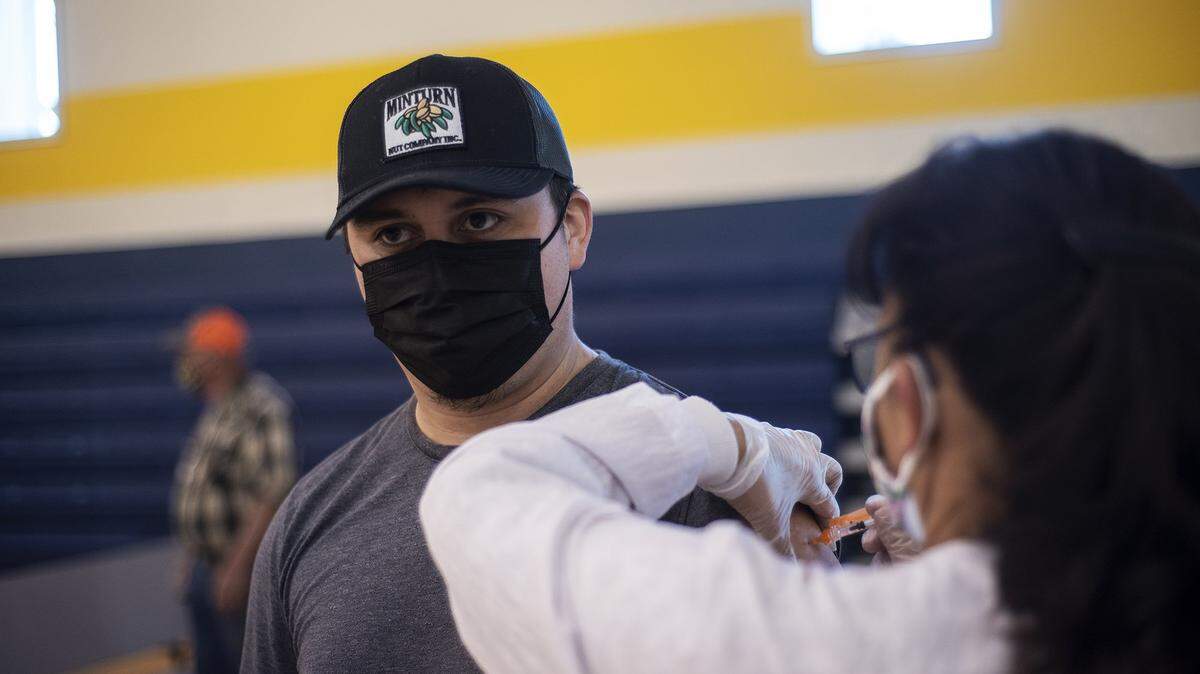 Rigoberto Tinoco, 27, of Planada, receives a COVID-19 vaccine administered by registered nurse Maria Contreras at a vaccination clinic inside the Cesar E. Chavez Middle School gymnasium in Planada, Calif., on Thursday, March 4, 2021.