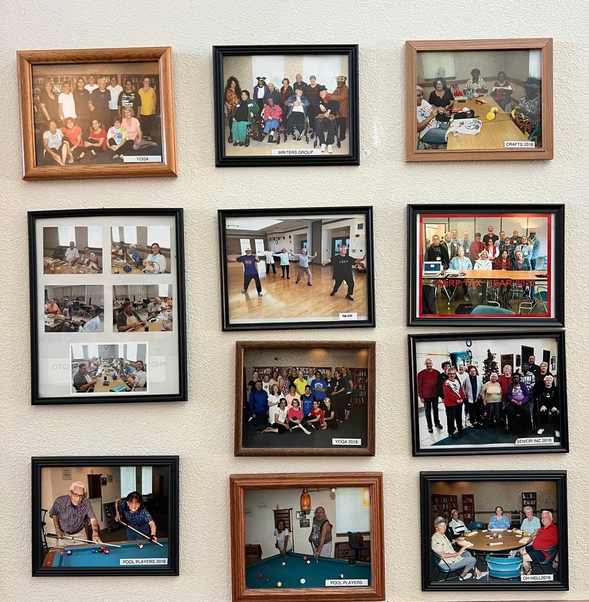 A wall at the Merced Senior Community Center showcases framed photographs of members engaged in various clubs and programs, including a writing group, Tai chi class, and woodcarving workshop.