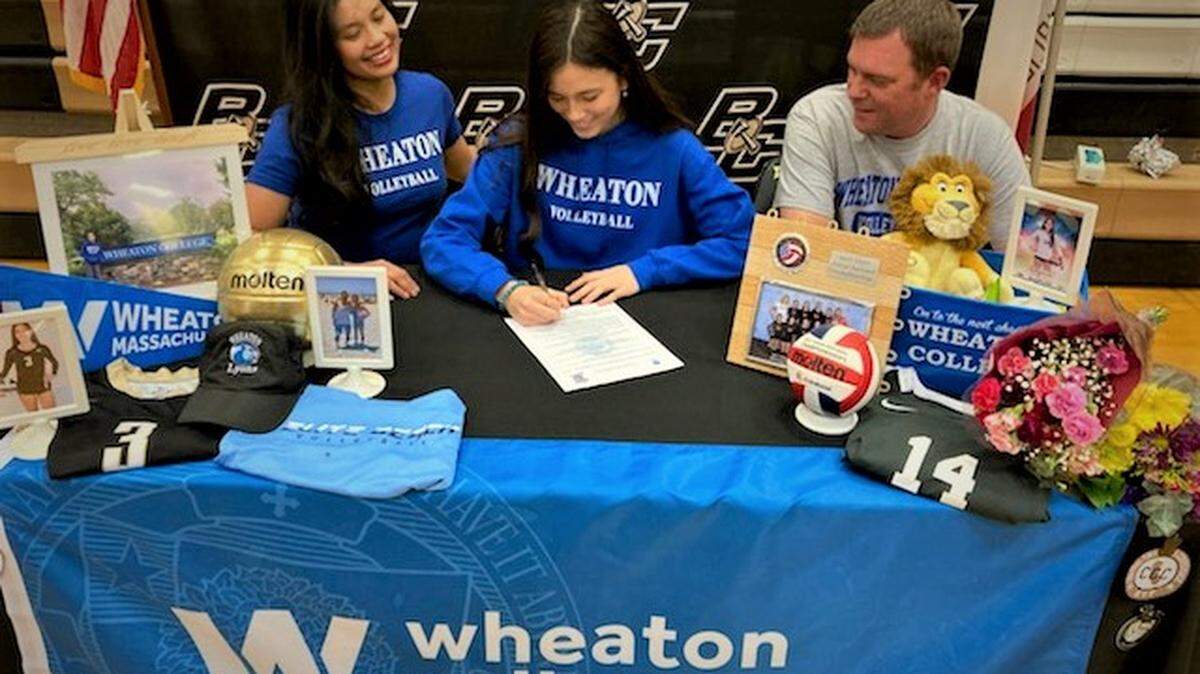 Buhach Colony senior Celina Henn signs her national letter of intent to play volleyball at Wheaton College while her mother Myra and father Chris look on during a ceremony at the Buhach Colony Gym.