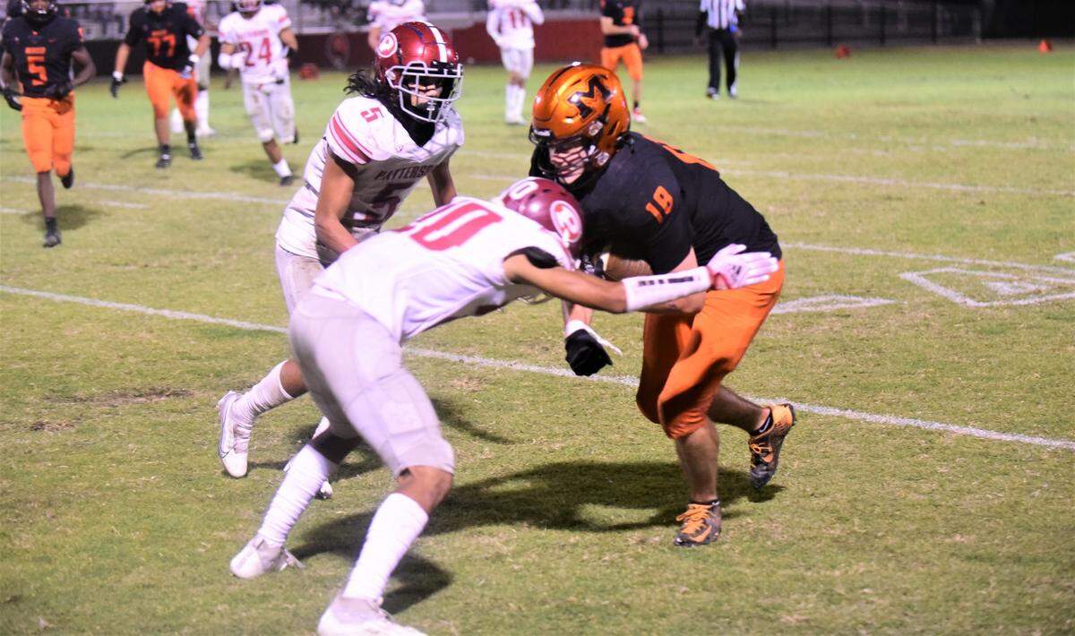 Merced High receiver Jack Collins tries to advance the ball against Patterson defenders Alvaro Granados (20) and Leo Refil (5) during a game on Friday, Sept. 23, 2022.