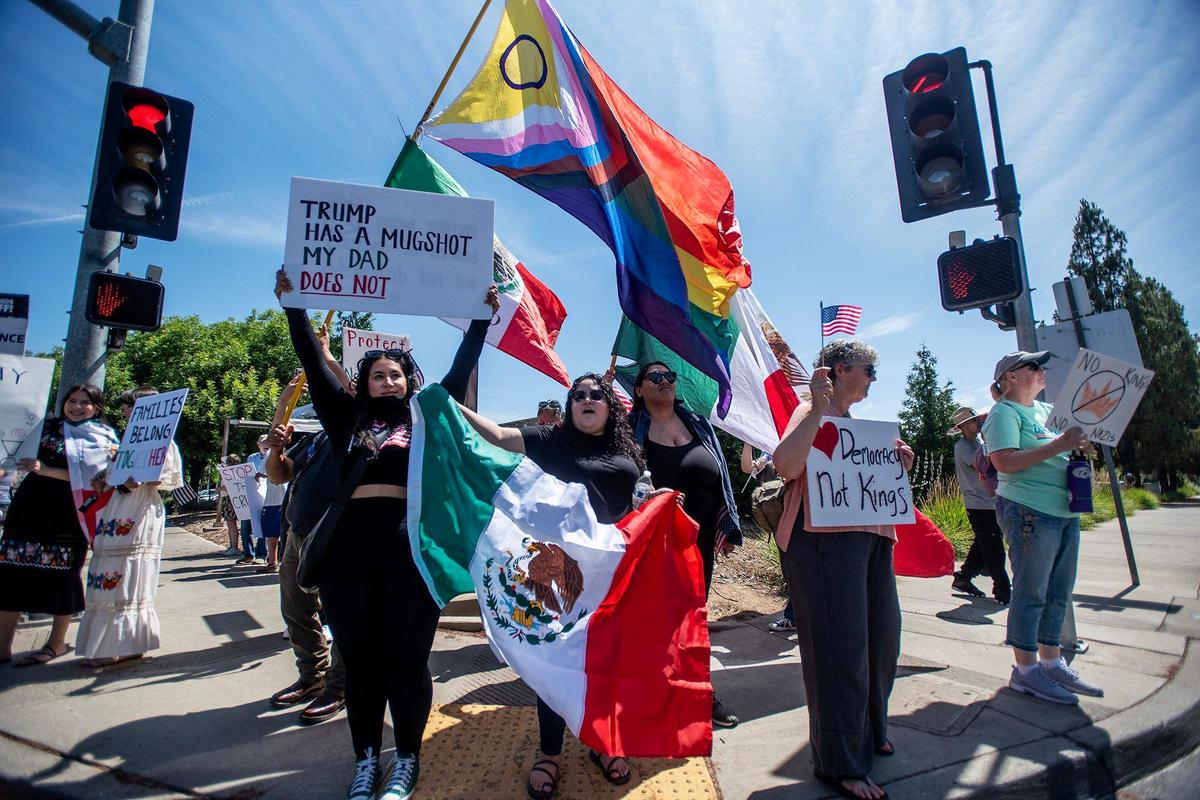 Protesters hold signs and wave flags as they take part in a “No Kings” protest in Merced, Calif., on Saturday, June 14, 2025.