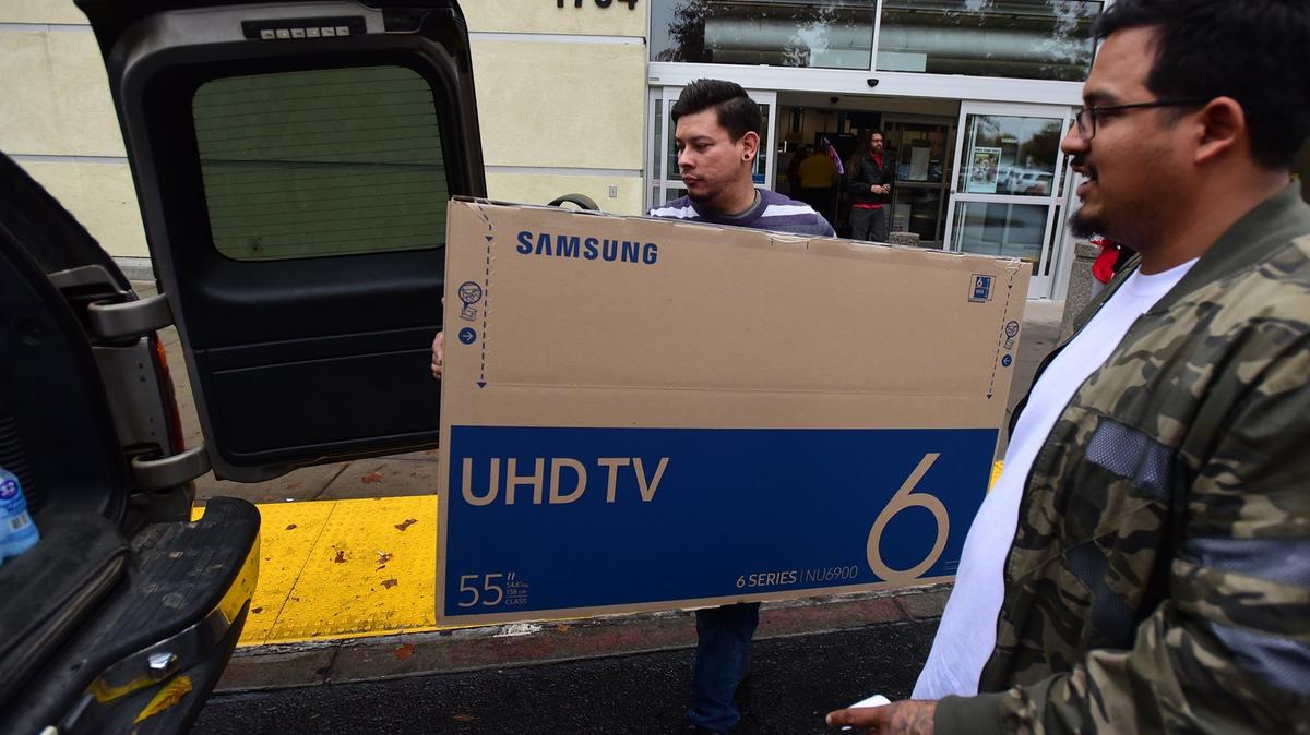 A Best Buy employee helps load a TV into the SUV of 28-year-old Steven Ortiz of Merced, left, on Friday, Nov. 23, 2018, which was also Black Friday.