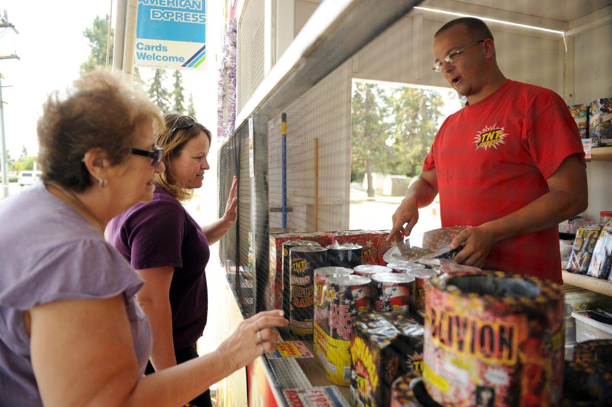 Dave Taylor, volunteer for the Merced High school Marching 100 Band, and an alumni of the band, (right) helps customers Marina Hoag (left) and Marina Lyon (middle) (mother and daughter), both of Merced, with their fireworks purchases at their stand on G St by Olive Ave in Merced Monday. (7-1-13). Lyon is buying the fireworks to celebrate her daughter Brittany Lyon’s birthday, which falls on the fourth. She will be 19.