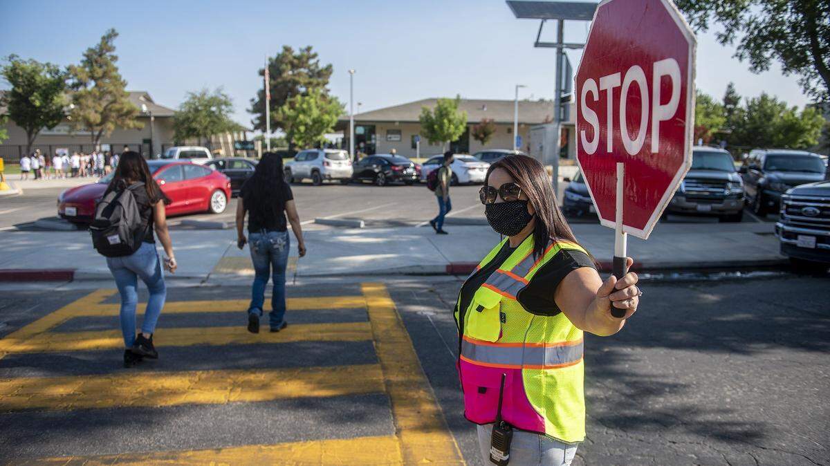 Elena Subia-Leal stops traffic as students cross the street on the first day of school at Rivera Middle School in Merced, Calif., on Wednesday, Aug. 11, 2021.
