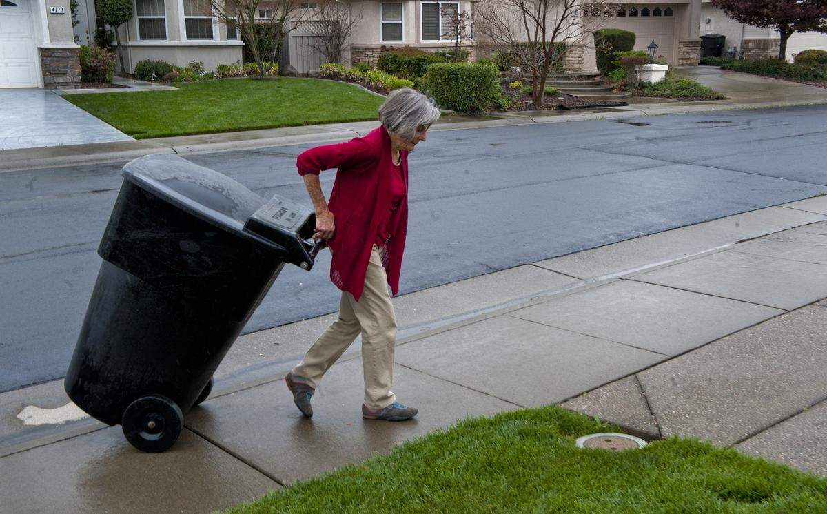 Lisa Smith brings in her garbage can in a recent rain. She says that she now has to leave herself sticky notes as reminders to do such simple tasks. She was diagnosed with mild cognitive impairment, which can progress to full-blown Alzheimer's disease