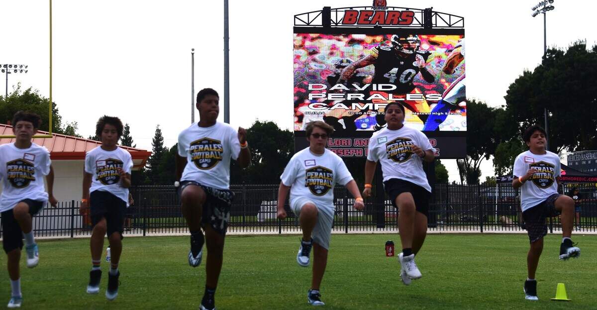 Players go through stretches prior to the start of the David Perales Football Camp on Saturday, July 13, 2024 at Merced High School.