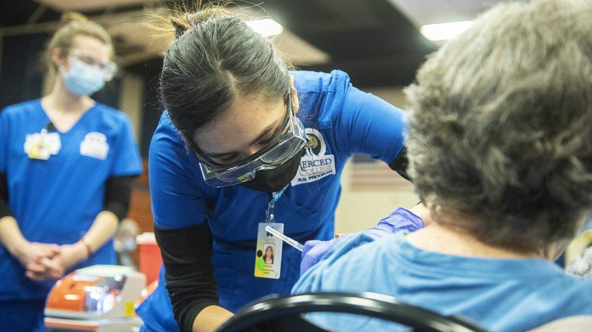 Merced College nursing student Dominique Romero, 22, of Los Banos, left, is shown administering a dose of the Pfizer COVID-19 vaccine to a patient at a vaccination clinic inside the Merced College gymnasium in Merced, Calif.