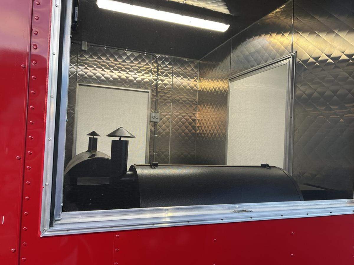 Two smokers seen through the window of the food truck.