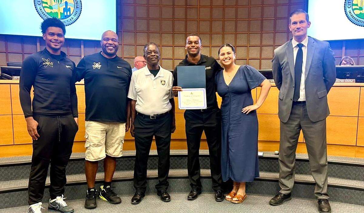 Brian Matthews, center, is recognized at a Merced City Council Meeting on Monday, July 15, 2024. Matthews, center, is pictured with high school teammate Naseem Hassaan, Brian’s youth and high school coach Raafeeq Hassaan, Brian’s father Andre Matthews, Brian’s fiancée Alana Simonian, and Mayor Matthew Serratto.