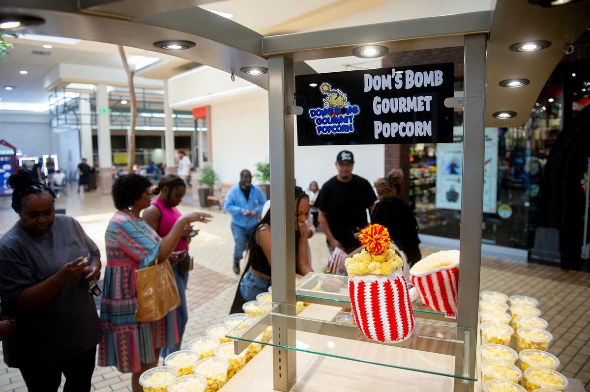 Customers line up to make purchases during the grand opening of Dom’s Bomb Gourmet Popcorn inside the Marketplace at Merced in Merced, Calif., on Thursday, May 1, 2025. The kiosk offers unique gourmet popcorn flavors created by Merced resident Dominique Pruitt.