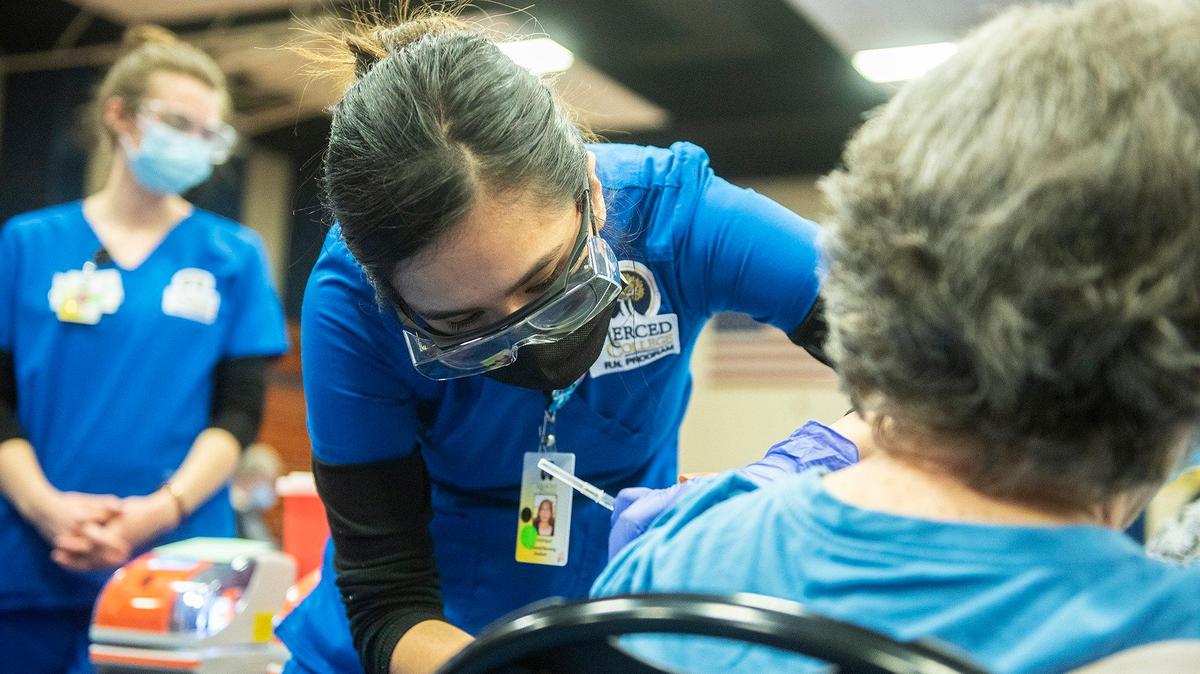 Merced College nursing student Dominique Romero, 22, of Los Banos, left, administers a dose of the Pfizer COVID-19 vaccine to a patient at a vaccination clinic inside the Merced College gymnasium in Merced, Calif., on Tuesday, Feb. 9, 2021. According to Merced College, the college partnered with University of California Health, UC Merced, Dignity Health Mercy Medical Center, Merced County and other volunteers and health practitioners to facilitate the clinic.