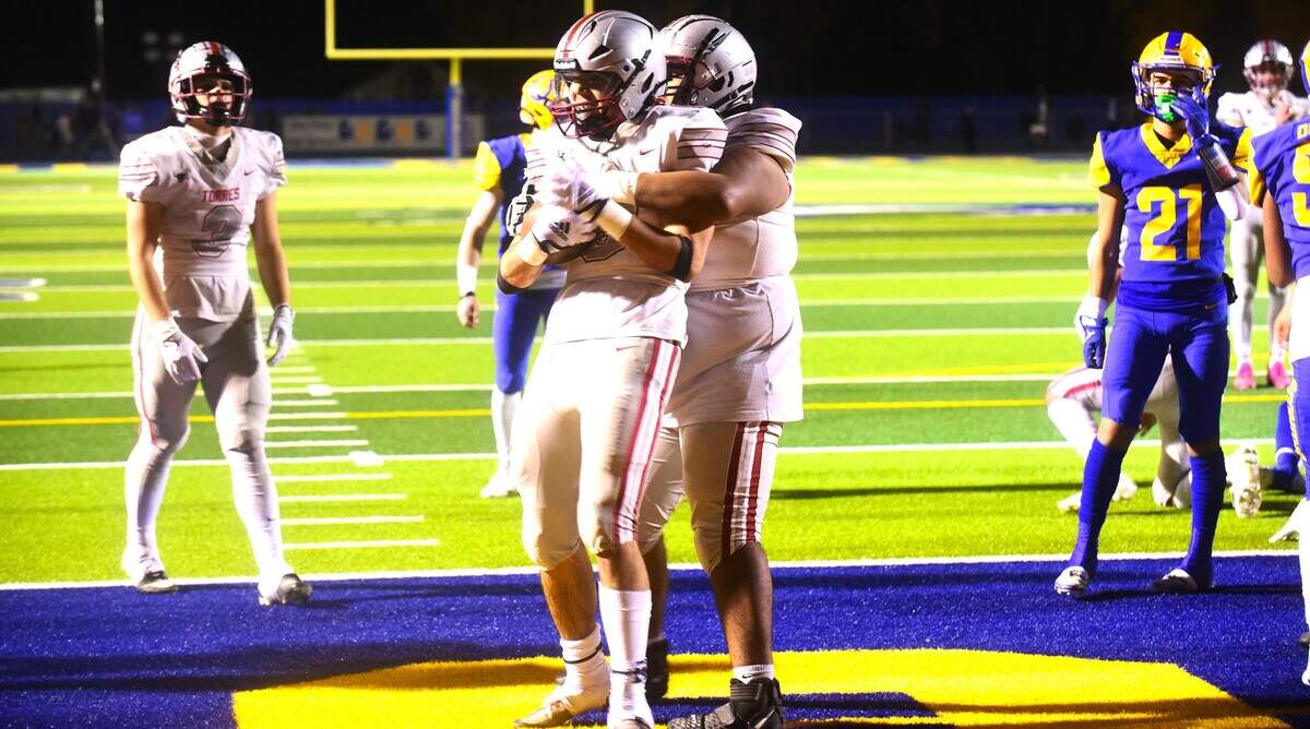 Torres High School running back Joseph Bass (3) is hugged by lineman Devan Henderson after Bass scored one of his three touchdowns during the Toros’ 69-14 win over Dos Palos in the Central Section Division IV championship game in Dos Palos, Calif.