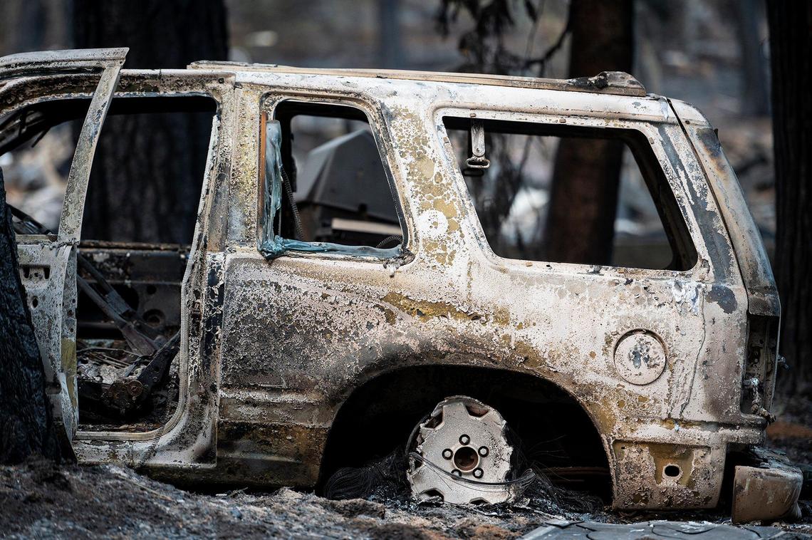 A charred vehicle sits on a property along Jerseydale Road as firefighters continue to battle the Oak Fire in Mariposa County, Calif., on Tuesday, July 26, 2022.