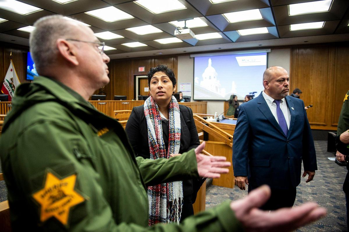 Daniela Ceja-Arceo, 25, of Planada, center, looks to Merced County Sheriff deputies after speaking with Supervisor Rodrigo Espinosa, right, as deputies ordered those in attendance of the the Merced County Board of Supervisors meeting to clear the room during a recess in Merced, Calif., on Tuesday, Feb. 28, 2023. The recess was called by District 5 Supervisor Scott Silveira, after Ceja-Arceo refused to quit speaking at the end of her allotted time while addressing the board during public comment. Planada residents and community advocates who attended the meeting said the county isn’t doing enough to help the community of Planada following devastating flooding which damaged homes and forced thousands to evacuate.