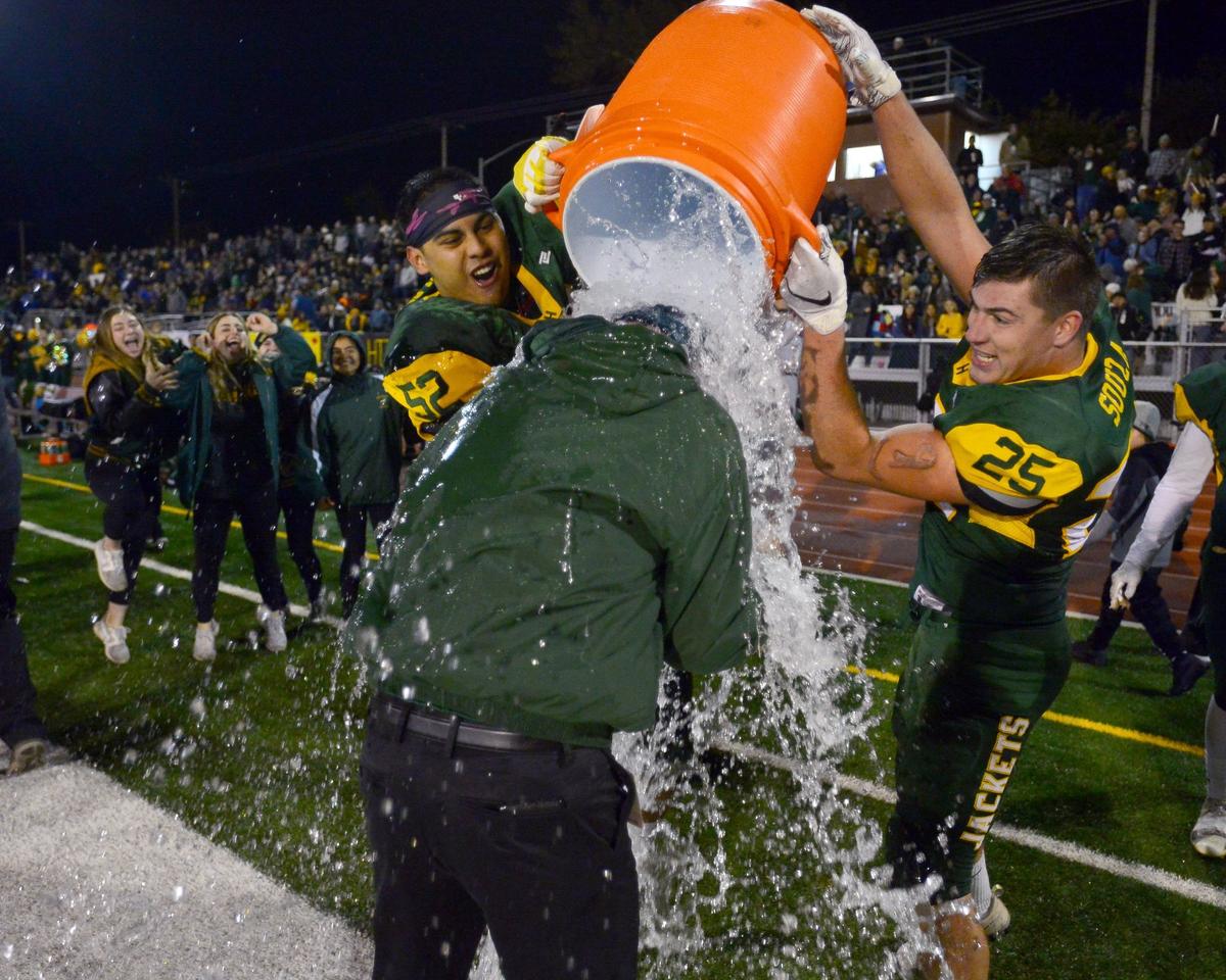 Hilmar players Justin Rentfro (right) and Nick Aguilera (left) celebrate by dousing their head coach Frank Marques  after winning the Division VI CIF Sac-Joaquin championship game over Ripon Christian at Turlock High School in Turlock CA on November 30, 2018.