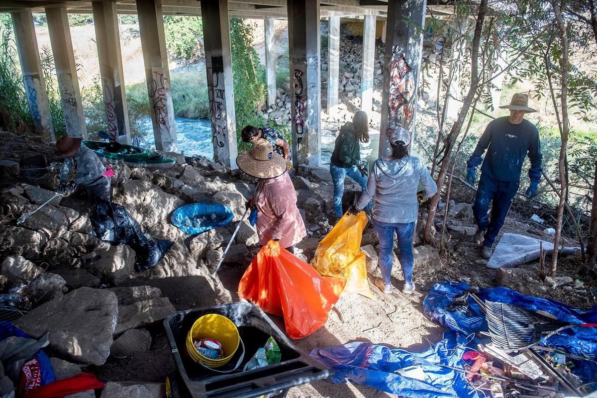 Volunteers clean up trash and debris from along the banks of Bear Creek beneath the McKee Road bridge during a cleanup event presented by the Merced non-profit Bear Creek Yacht Club in Merced, Calif., on Saturday, Oct. 14, 2023.