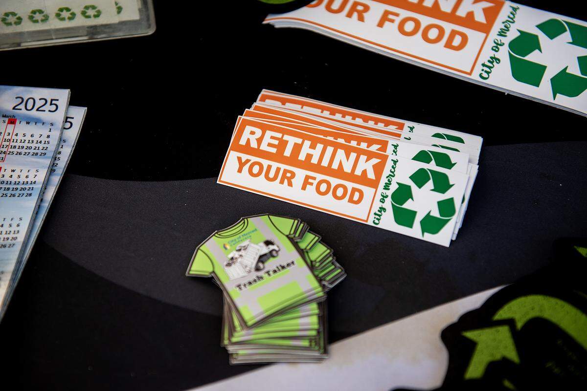 Various give away items with information about recycling sit on the table as City of Merced Recycling Coordinator Monique Gama, interacts with members of the community during the National Night Out event at Applegate Park in Merced, Calif., on Tuesday, Aug. 5, 2025. 