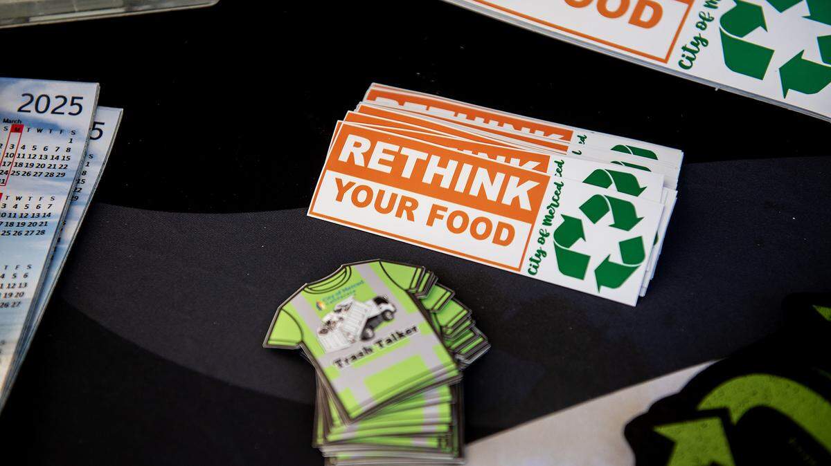 Various give-away items with information about recycling sit on the table during a public information event.