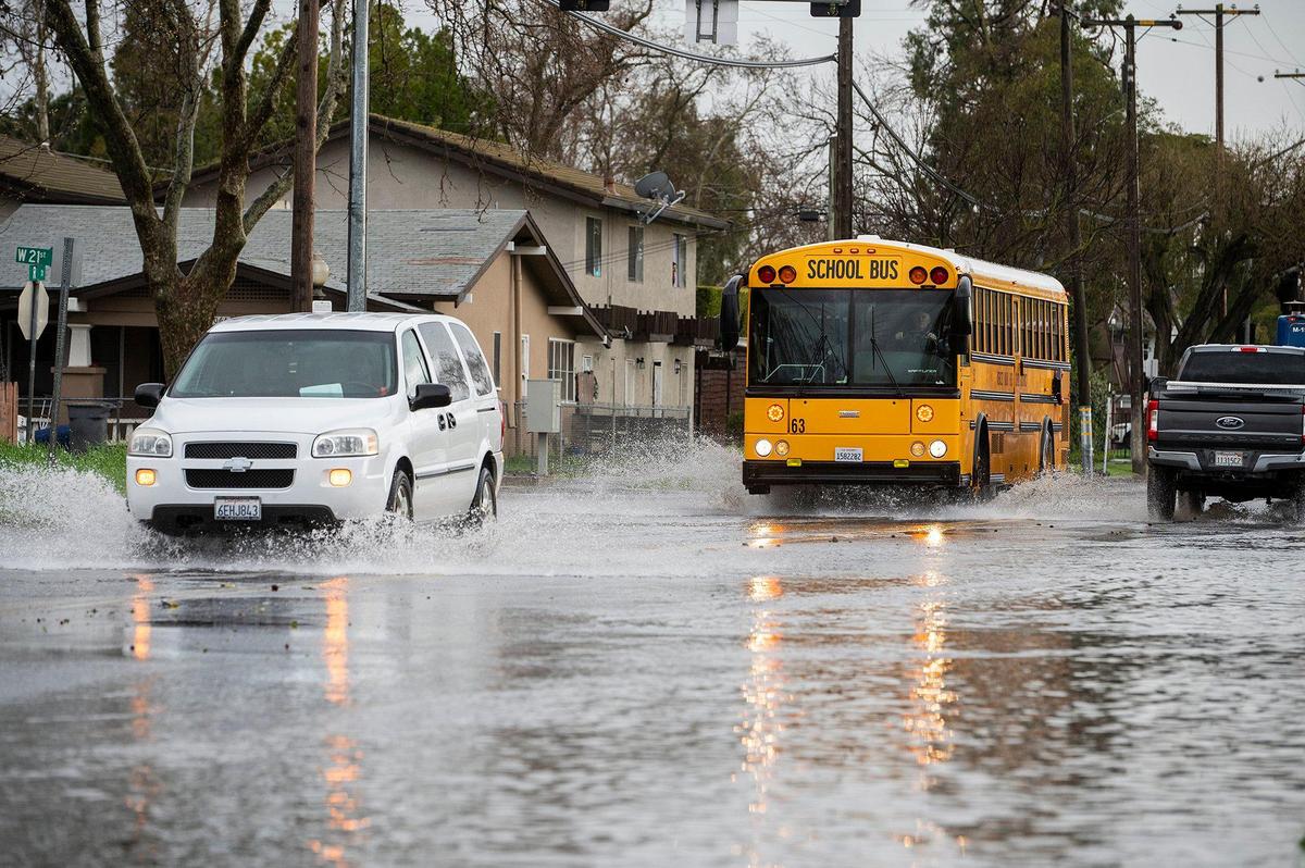 Motorists navigate a flooded section of R Street near the intersection with West 22nd Street in Merced, Calif., on Tuesday, March 14, 2023.