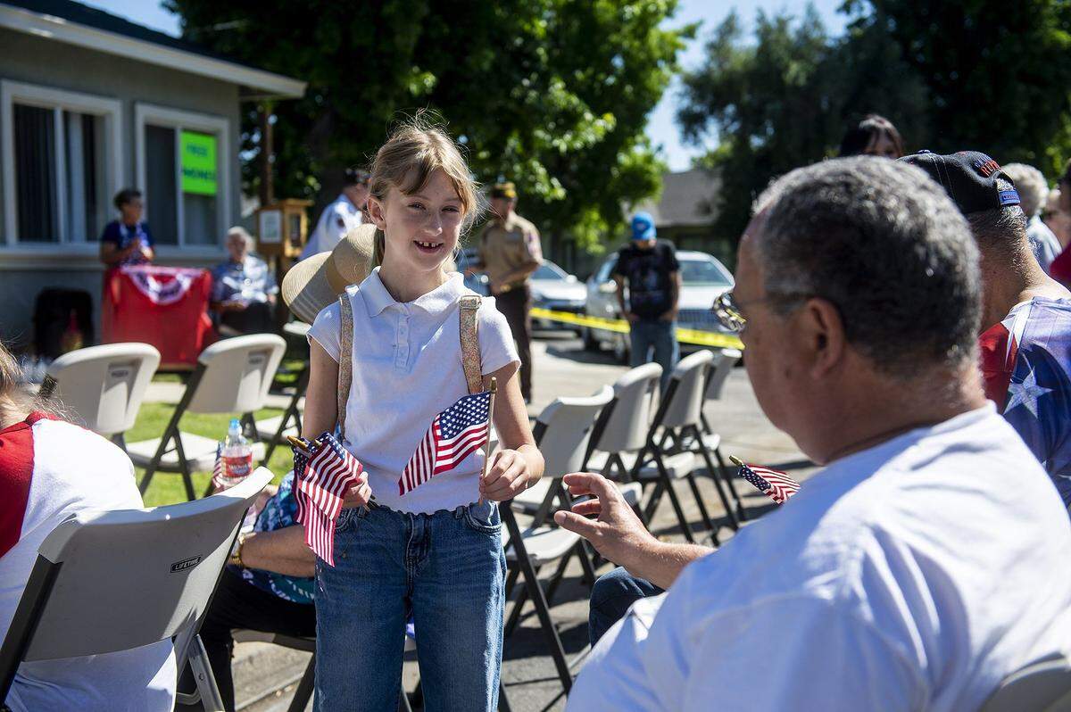 Madelyn Duckworth, 8, passes out small American flags to those in attendance during a flag raising ceremony inside the Castlewood community in Atwater, Calif.